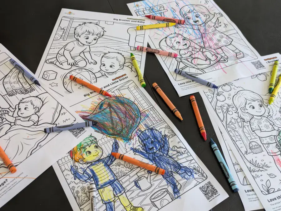 Free Happy Crayon Studios colouring pages spread out on a table with crayons, some already coloured in by little hands